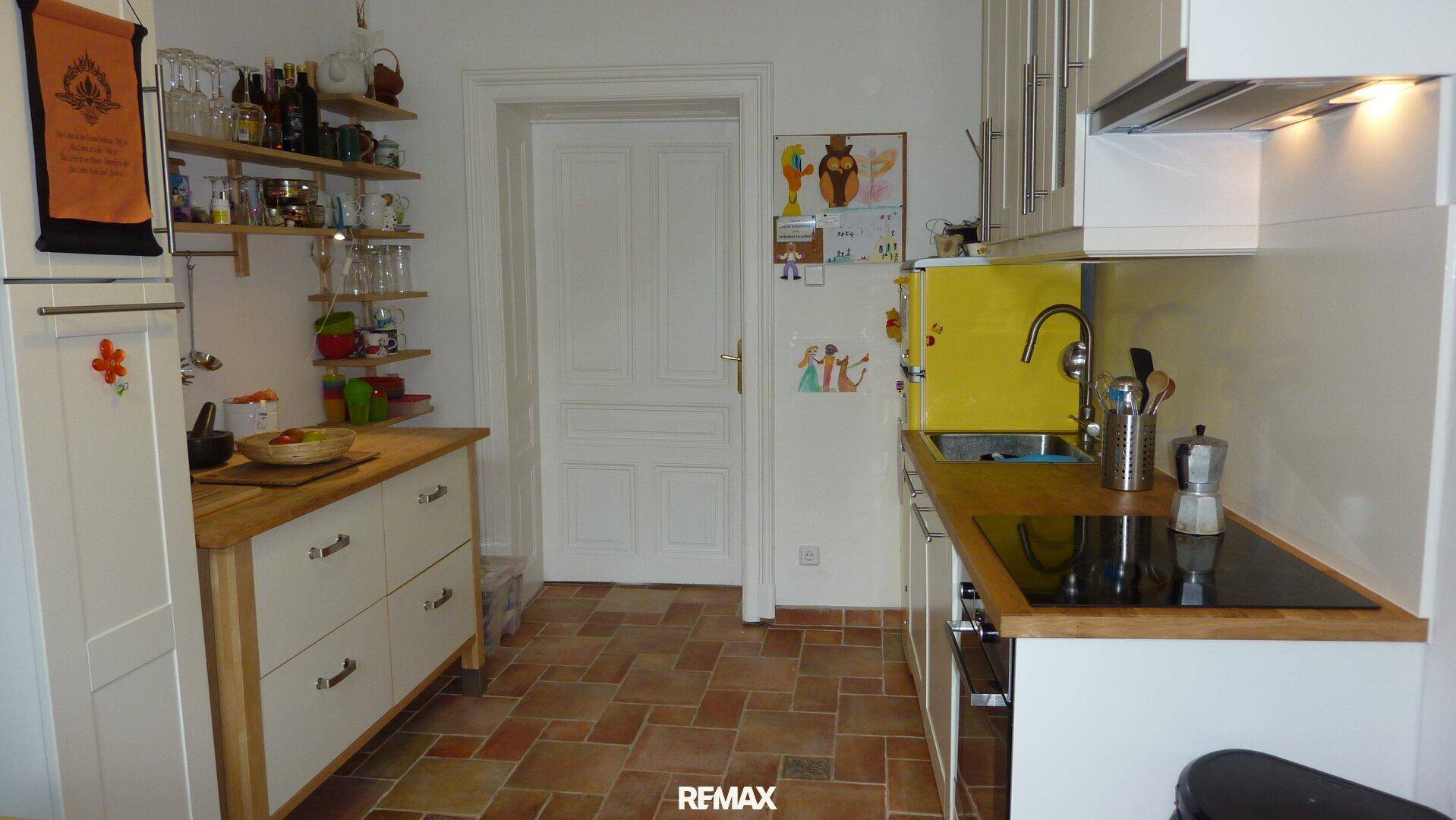 Funktionale Küche mit Induktionskochfeld, Spüle, Holz-Arbeitsplatten und praktischen Regalen.