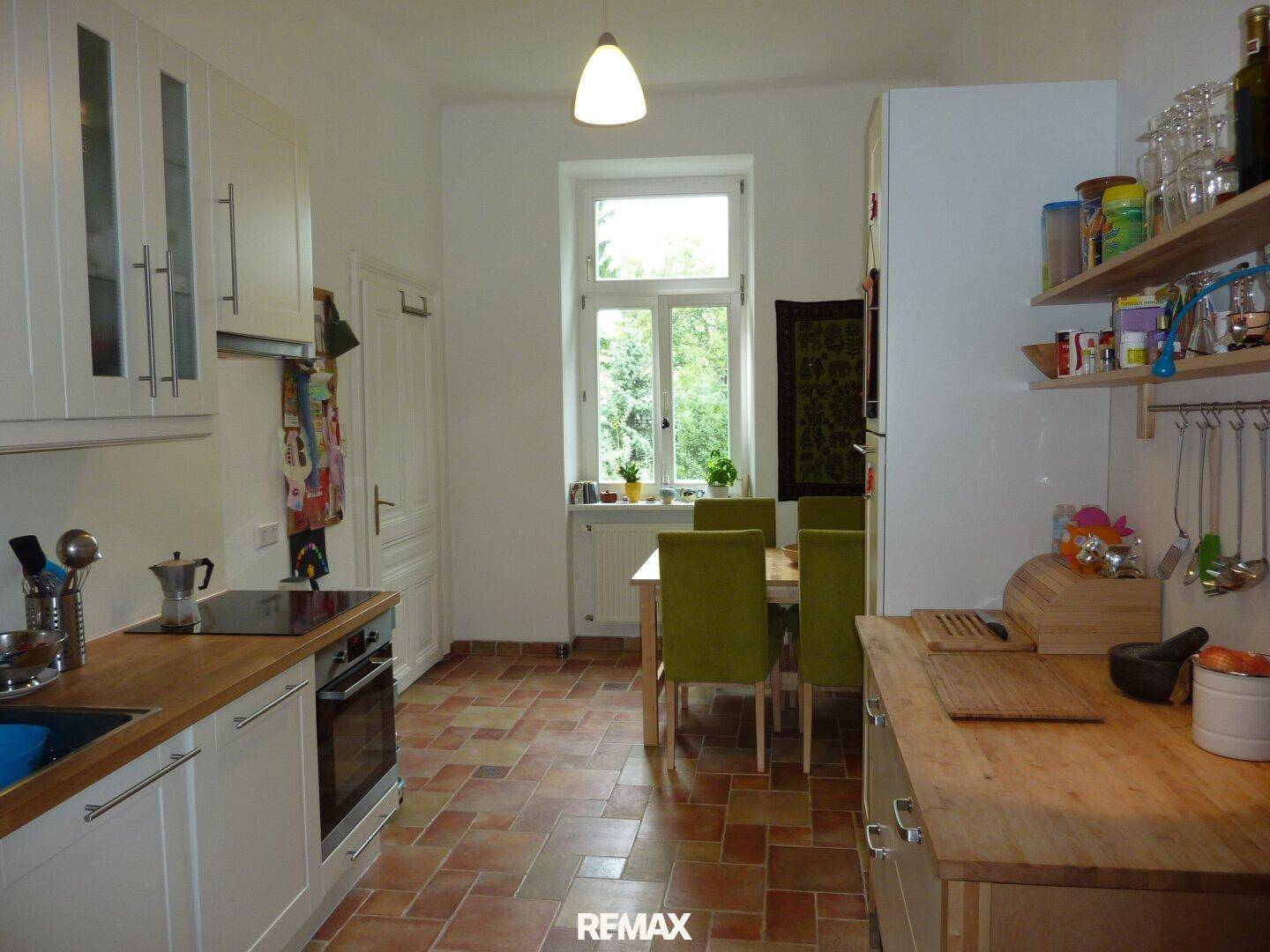 Gemütliche Küche mit Essbereich, Holz-Arbeitsplatten, Terrakotta-Fliesenboden und Blick ins Grüne.