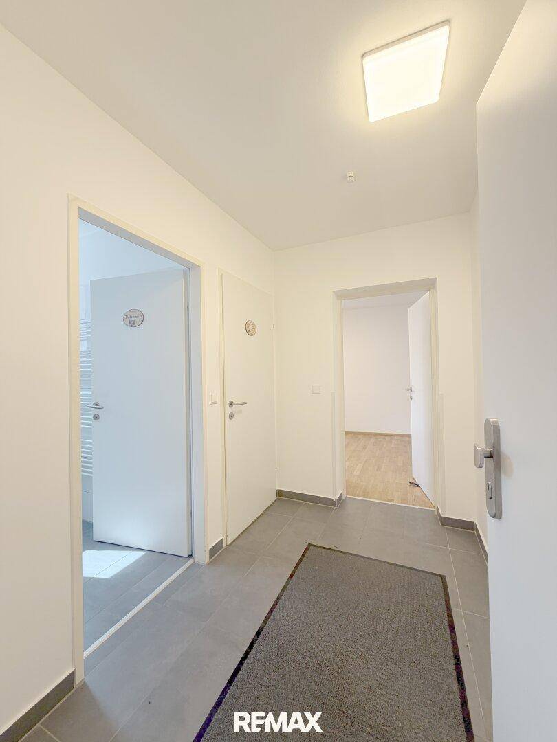 Heller Flur mit Fliesenboden, weißen Wänden und Zugang zu verschiedenen Zimmern.