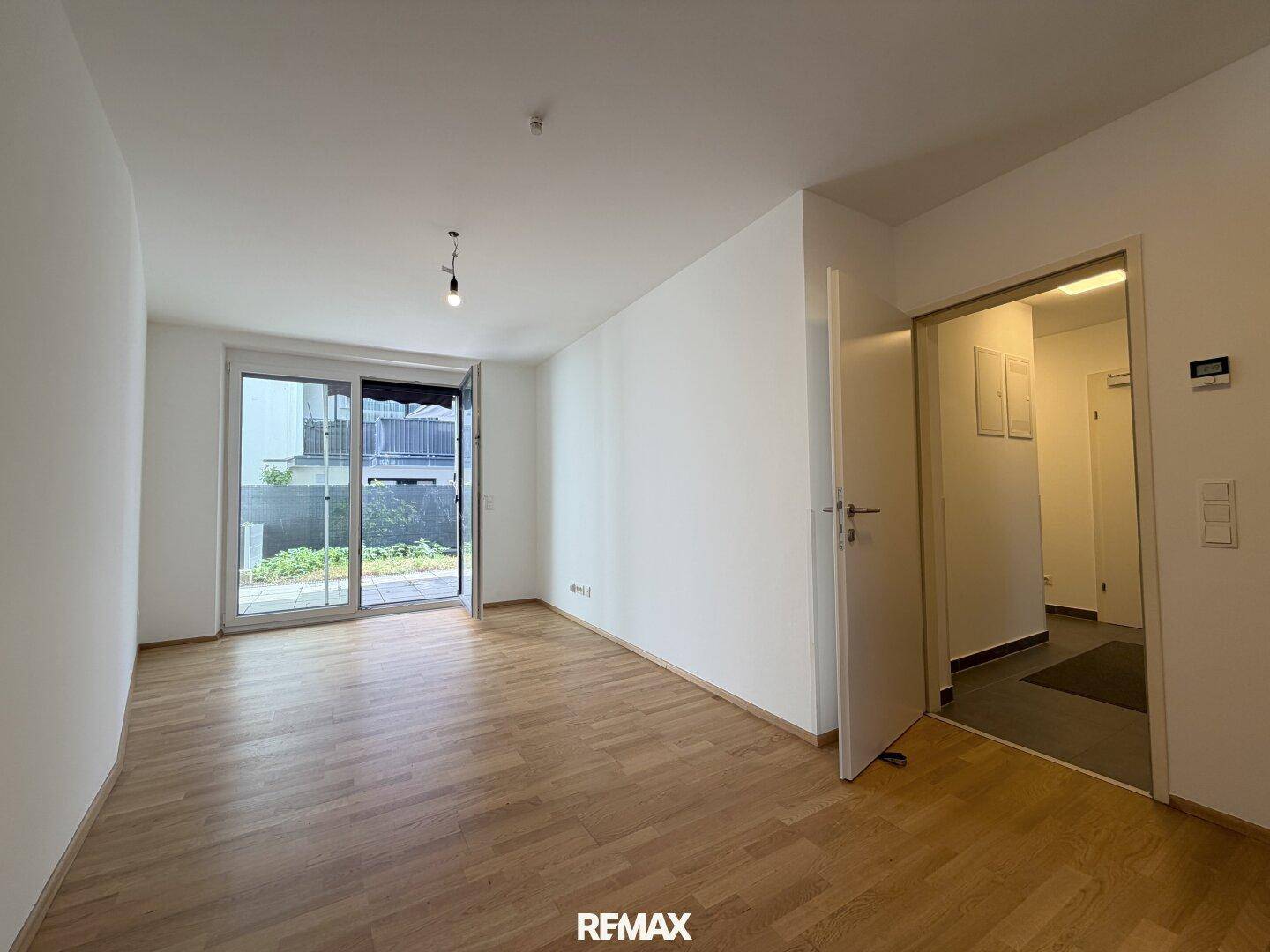 Helles, leeres Wohnzimmer mit Parkettboden und Zugang zur Terrasse im Erdgeschoss.