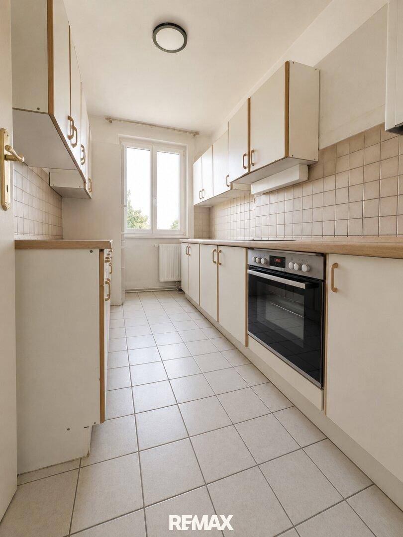 Funktionale Küche mit weißen Schränken, Holz-Arbeitsplatten und Fliesenboden.