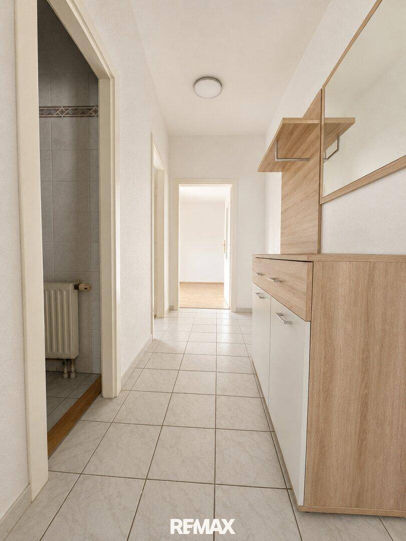 Heller Flur mit Fliesenboden und Garderobenmöbeln, der zu weiteren Räumen führt.