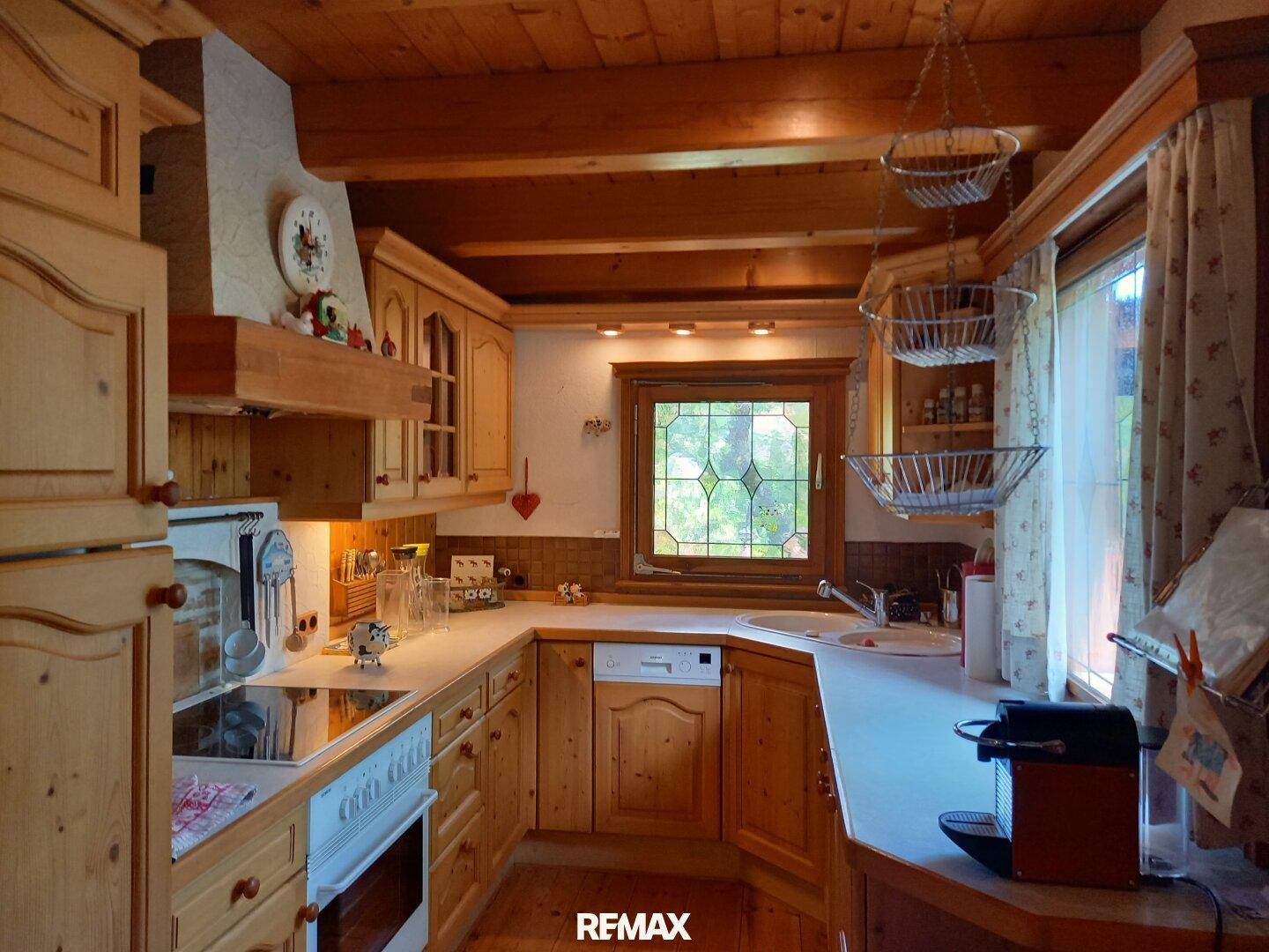 Gemütliche Holzküche im Landhausstil mit Einbaugeräten, Bleiglasfenster und Holzbalkendecke.