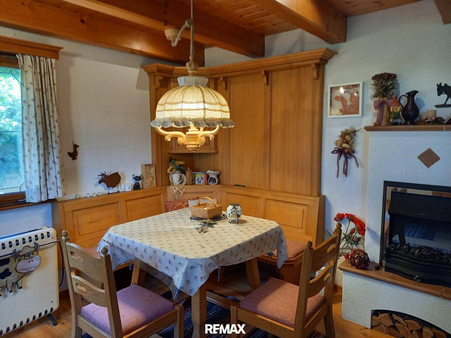 Rustikaler Essbereich mit Holztisch, Eckbank und traditionellem Kaminofen in gemütlicher Atmosphäre.