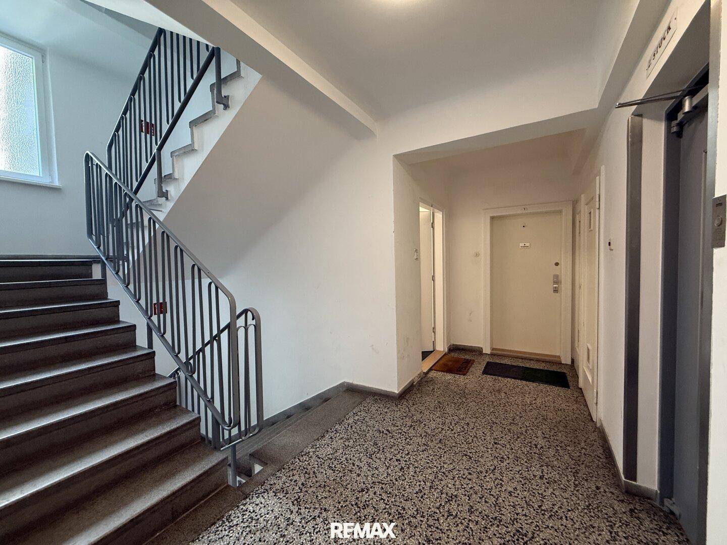 Treppenhaus eines Mehrfamilienhauses mit Terrazzoboden und Zugang zu den Wohnungen.