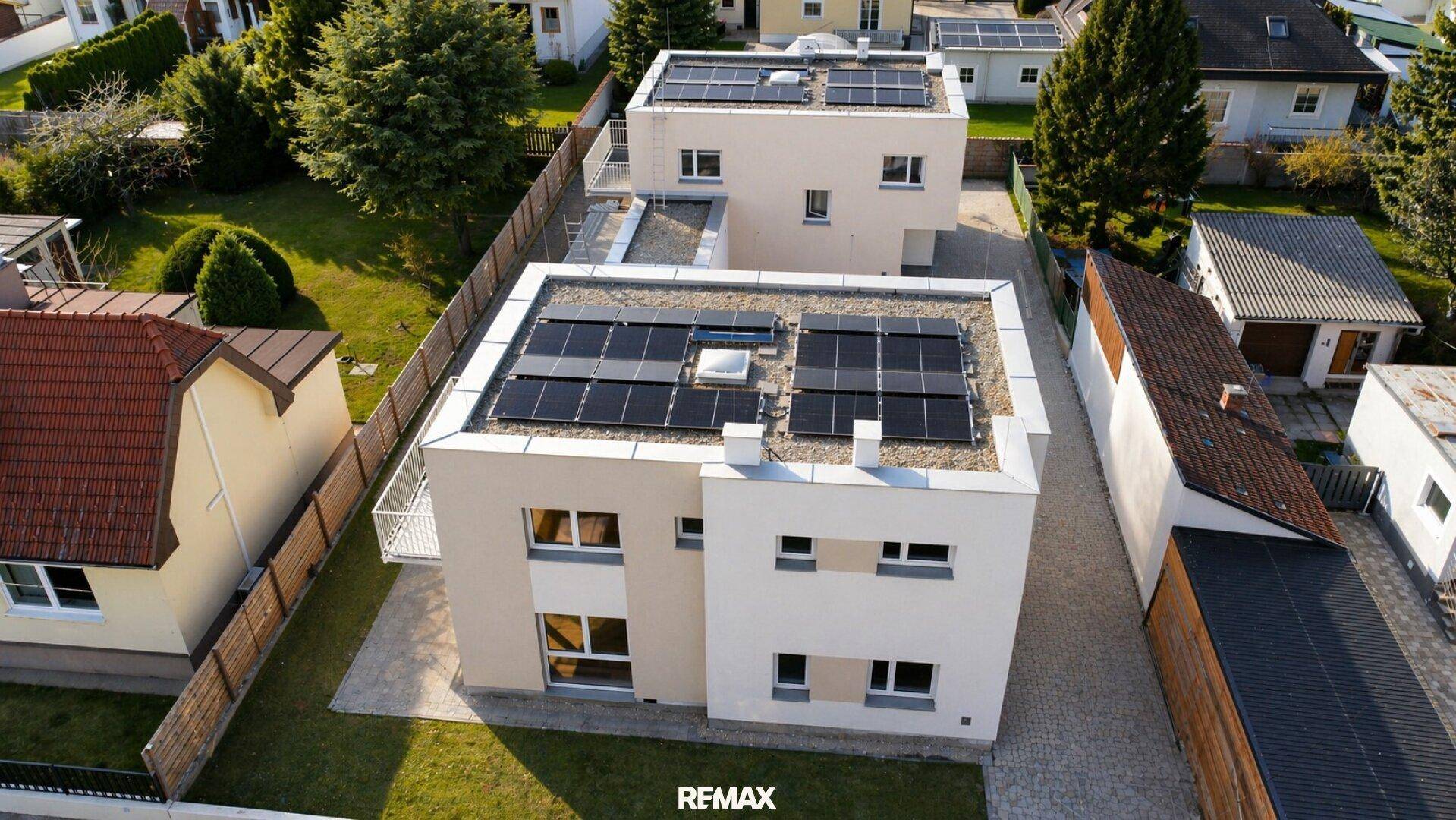 Luftaufnahme von modernen Gebäuden mit Flachdächern und installierten Photovoltaikanlagen.
