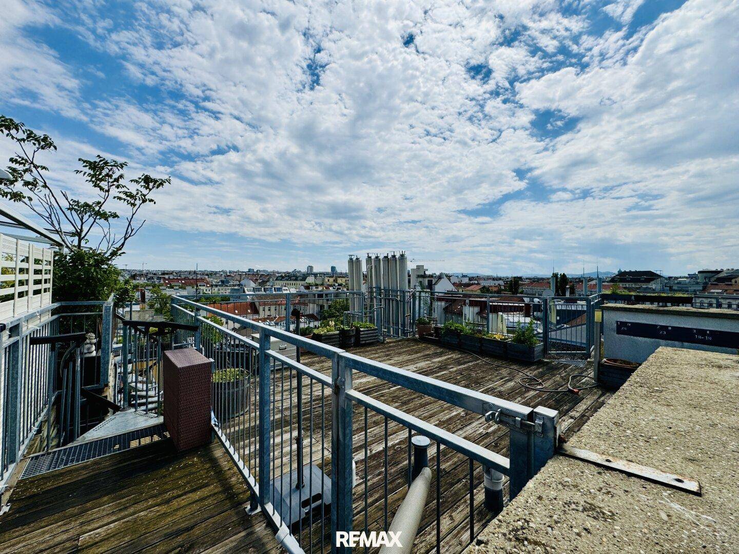 Geräumige Dachterrasse mit Holzboden und weitem Blick über die Stadt.