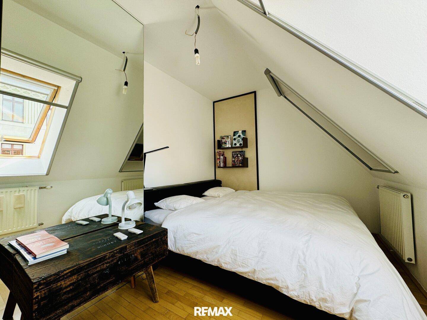 Gemütliches Schlafzimmer mit Doppelbett, Holzboden und Dachfenstern für Tageslicht.