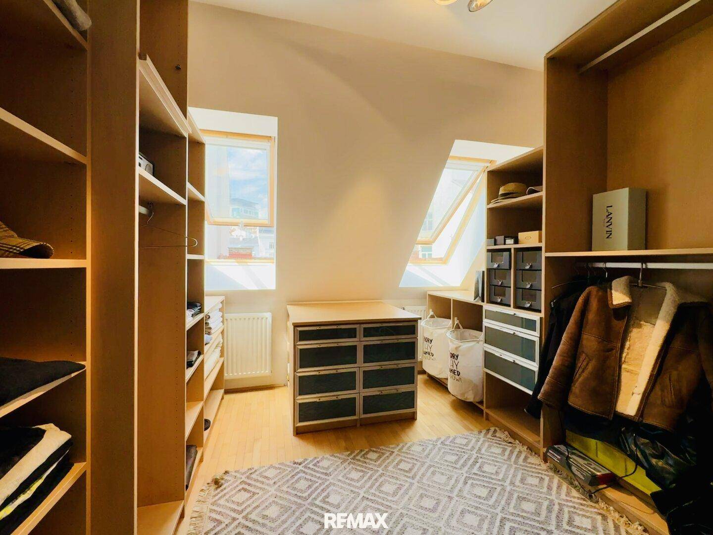 Geräumiger begehbarer Kleiderschrank mit vielen Regalen, Schubladen und Dachfenstern.