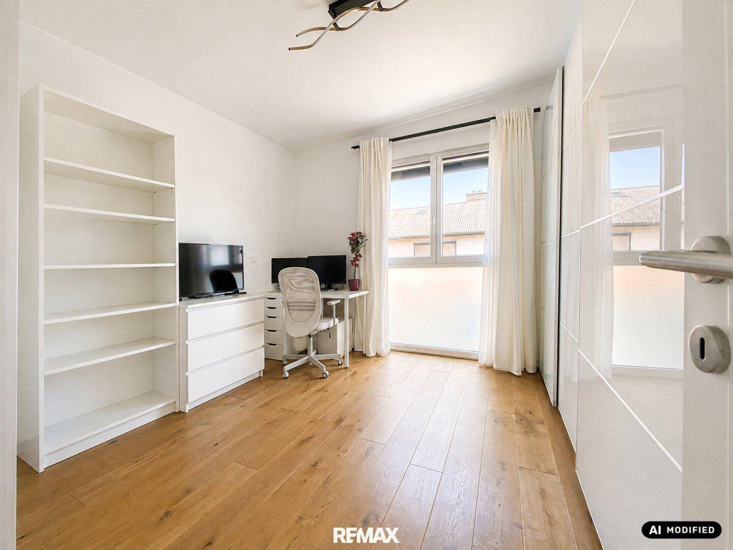 Helles Arbeitszimmer mit Holzboden, Schreibtisch und Bücherregal.