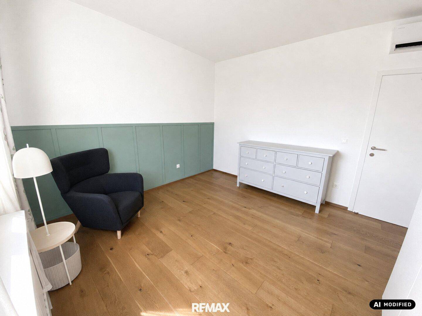 Schlafzimmer mit Holzboden, Kommode und grün gestrichener Wand.