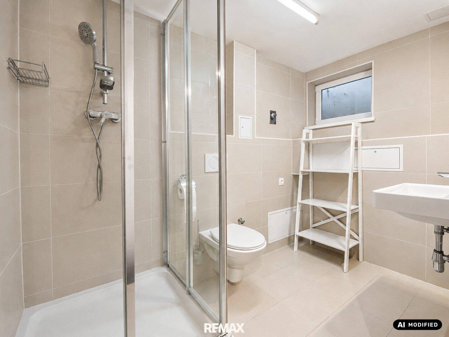 Badezimmer im Keller mit Dusche, WC und beigen Fliesen.