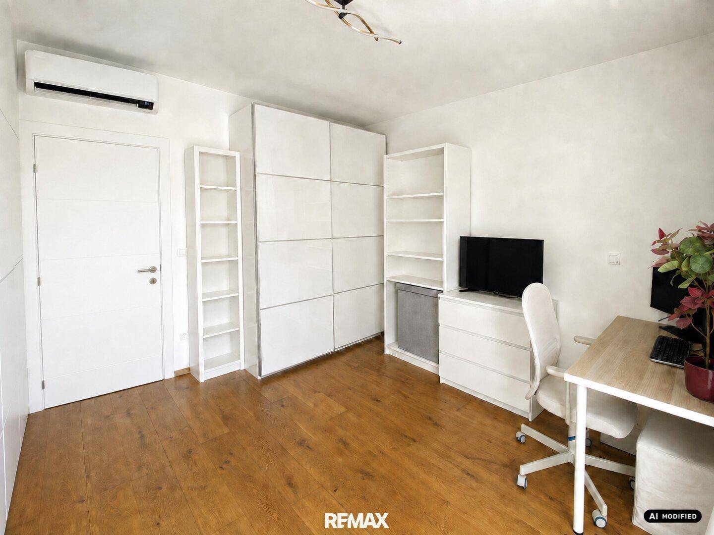 Arbeitszimmer mit Holzboden, Schrankwand und Klimaanlage.