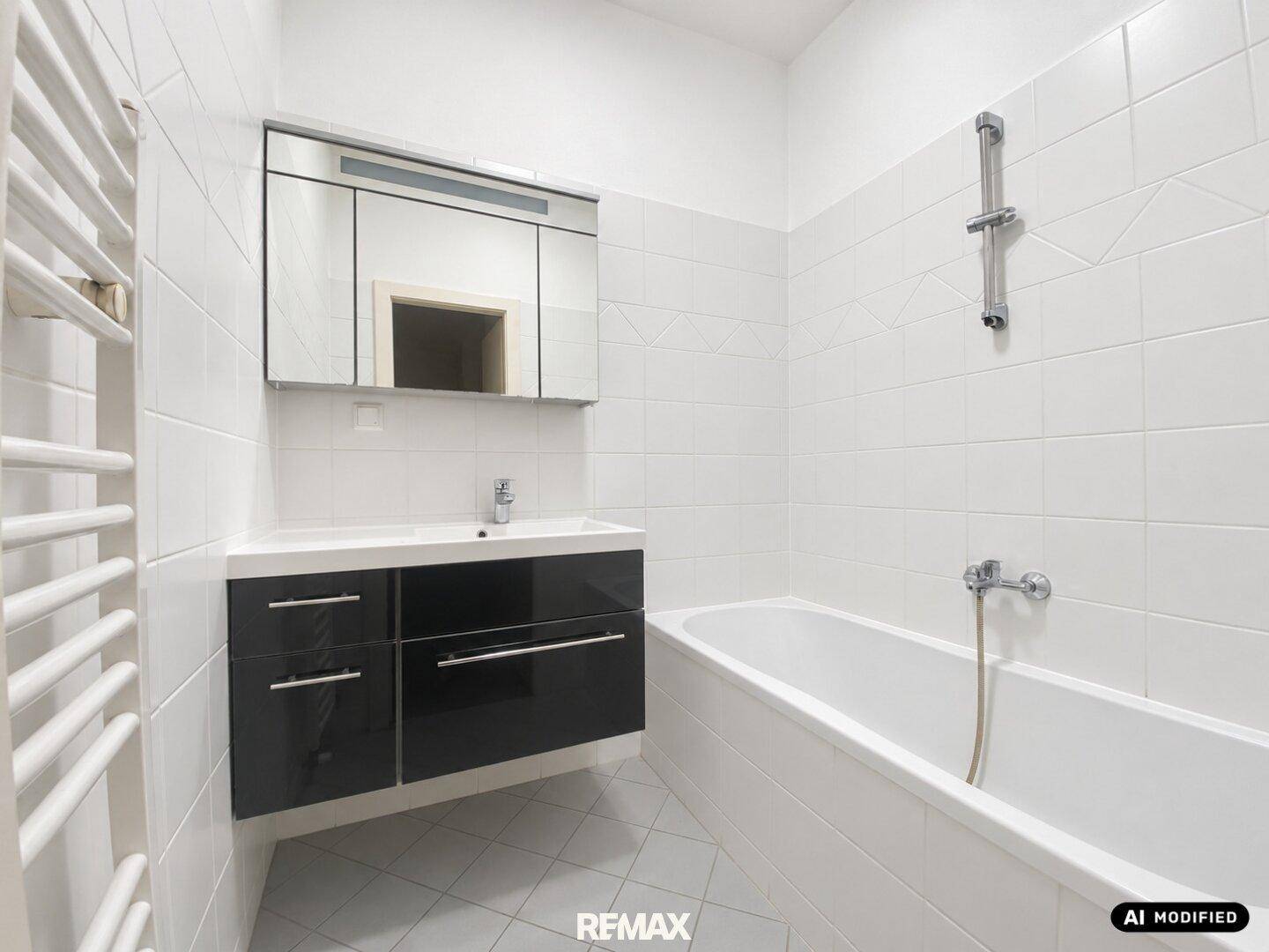 Gefliestes Badezimmer mit Badewanne, Waschbeckenunterschrank und Spiegelschrank.