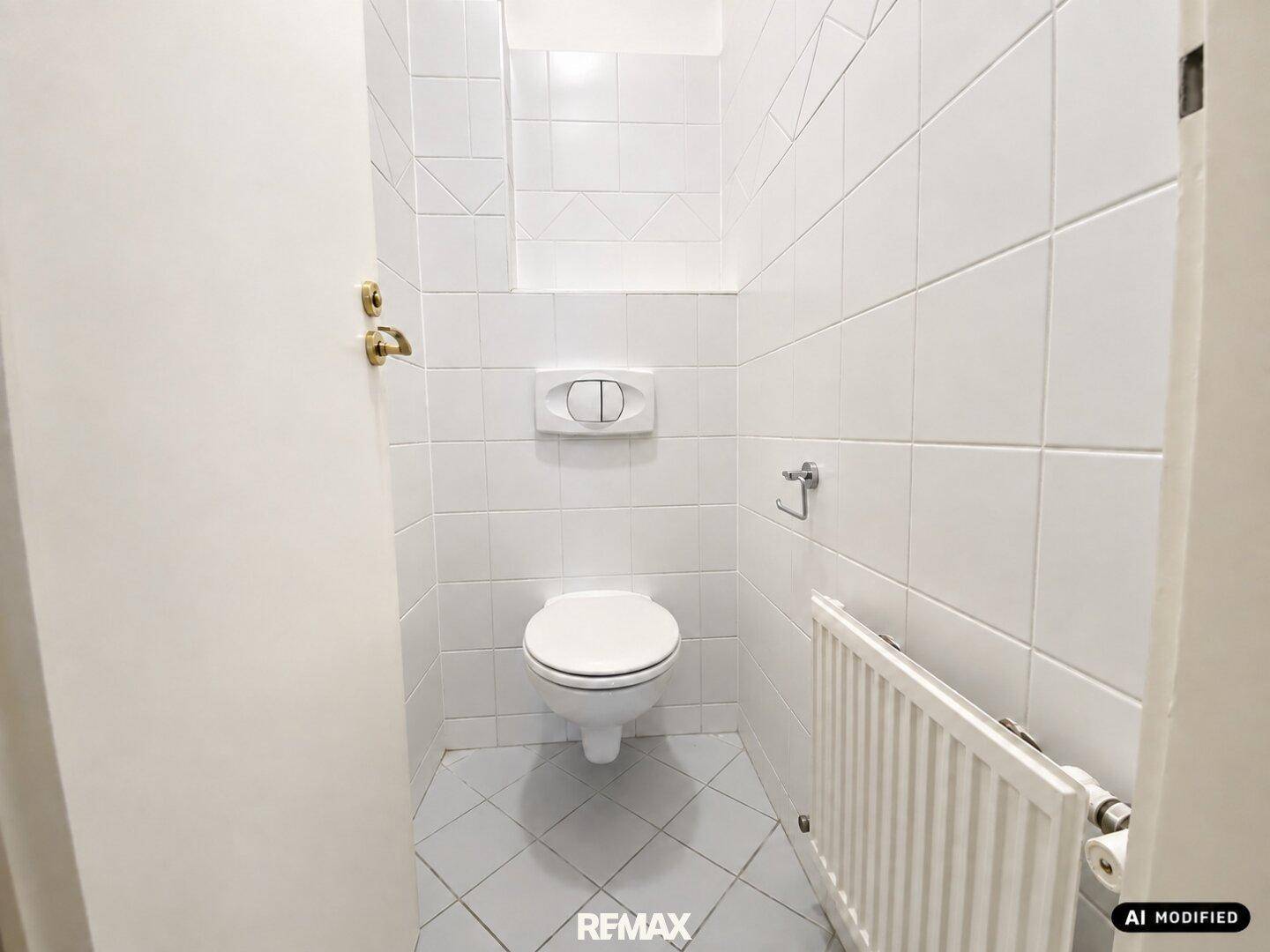 Kleines, vollständig gefliestes Gäste-WC mit wandhängender Toilette und Heizkörper.