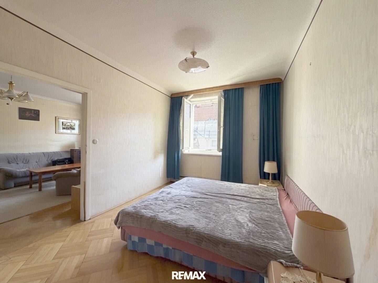 Schlafzimmer mit Parkettboden, Doppelbett und einem Fenster, das für natürliches Licht sorgt.