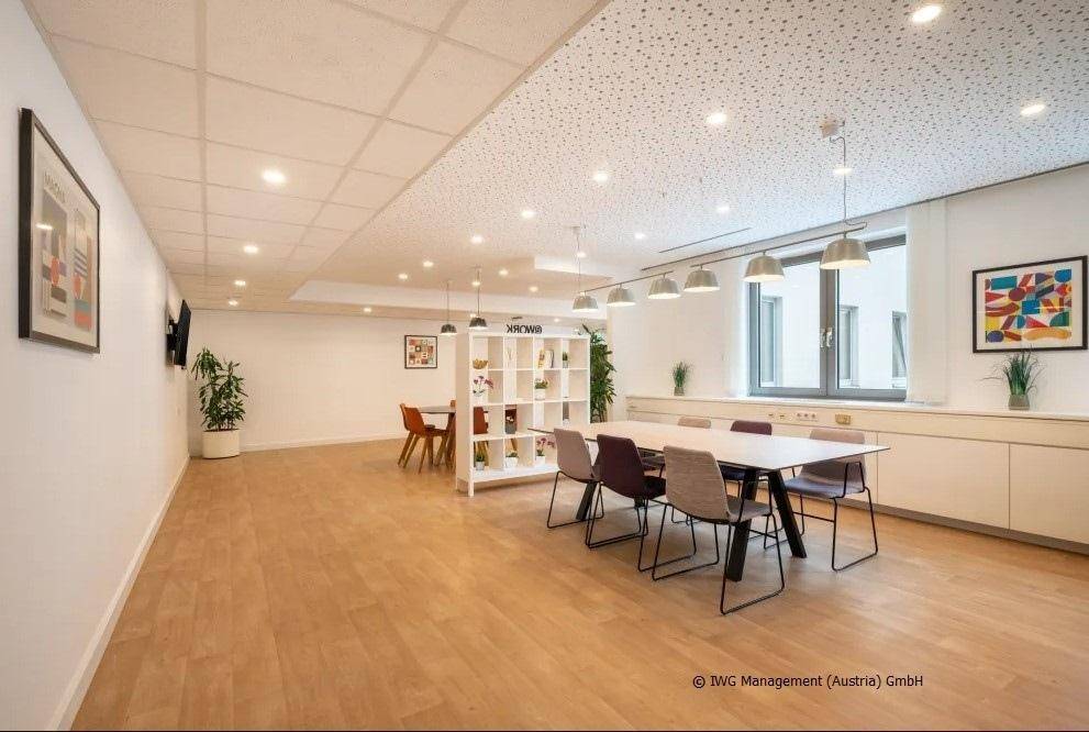 Geräumiger Gemeinschaftsbereich mit Holzboden, verschiedenen Sitzgelegenheiten und moderner Deckenbeleuchtung.