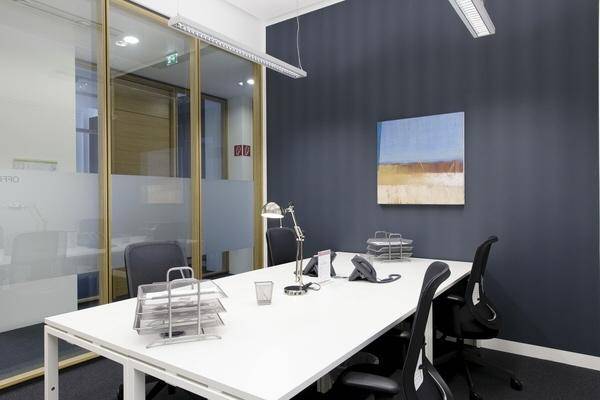 Modernes Büro mit Glastrennwand, dunkler Wandfarbe und mehreren Schreibtischen für effizientes Arbeiten.