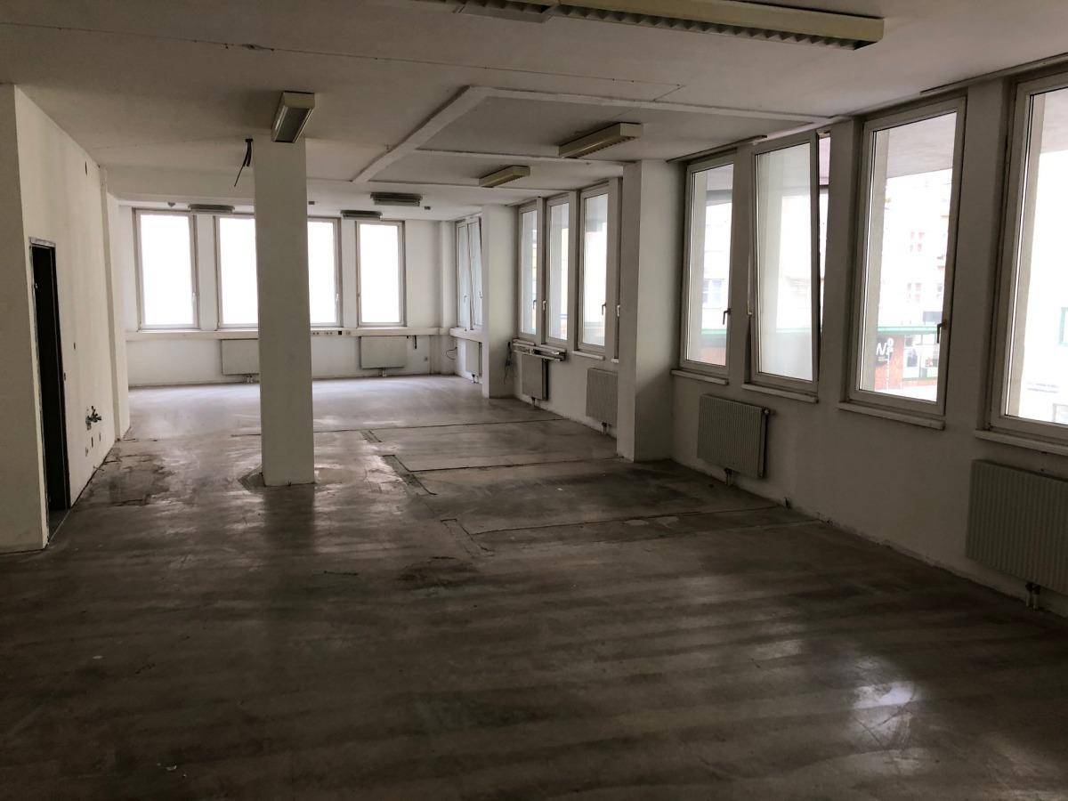 Weitläufiger, leerstehender Büroraum mit vielen Fenstern und sichtbaren Heizkörpern, bereit zur Neugestaltung.
