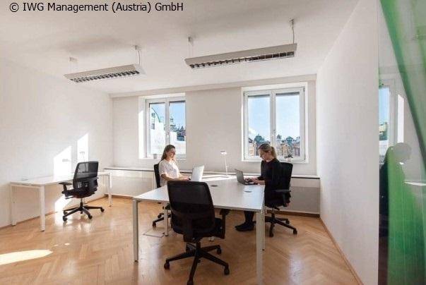 Helles Büro mit Holzboden, modernen Arbeitsplätzen und Blick auf die Stadt.