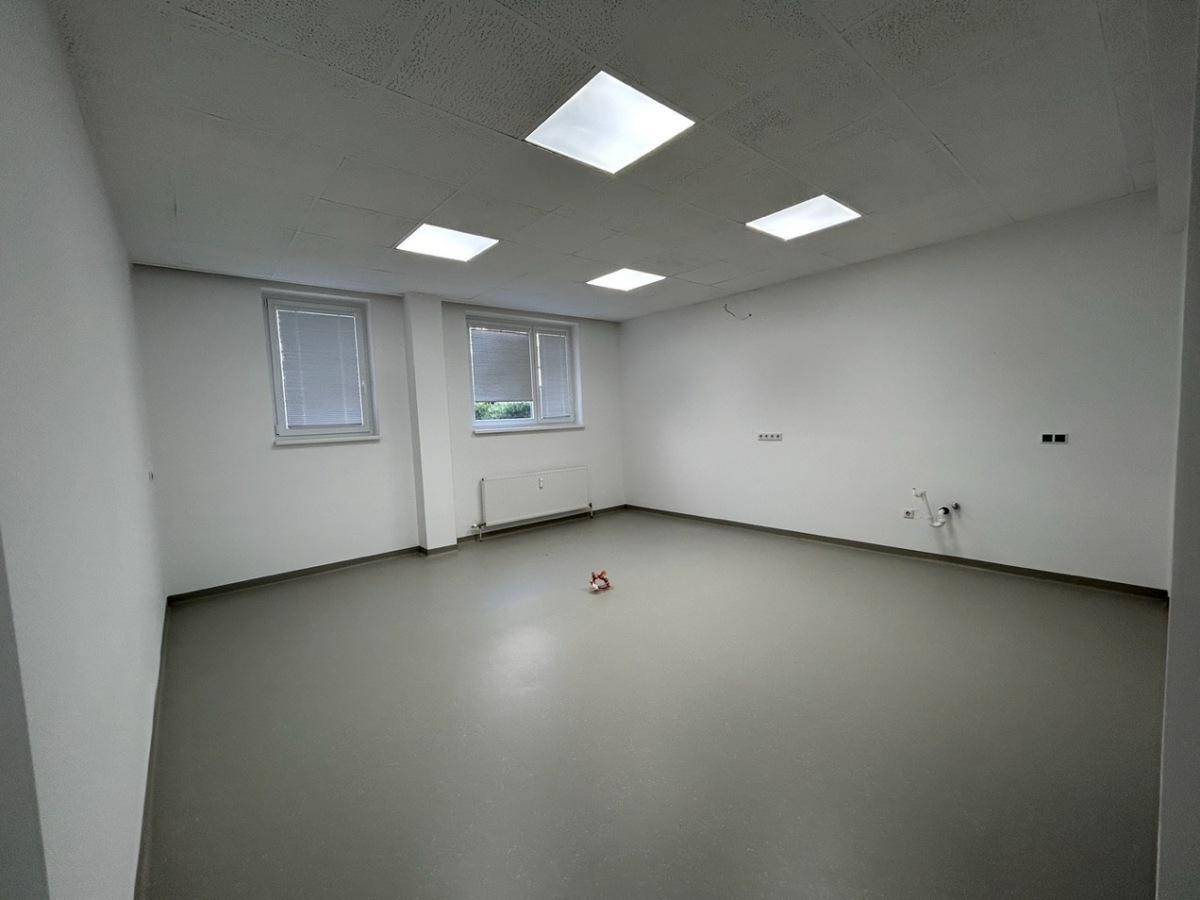 Leerer Büroraum mit zwei Fenstern, hellem Boden und weißen Wänden, ideal für flexible Nutzung.
