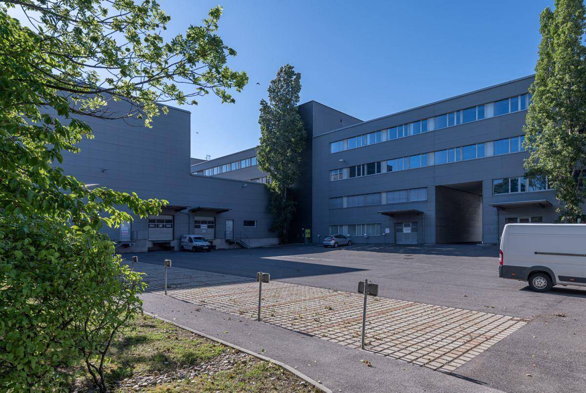 Großes Gewerbegebäude mit grauer Fassade, Laderampen und einem geräumigen Parkplatzbereich.