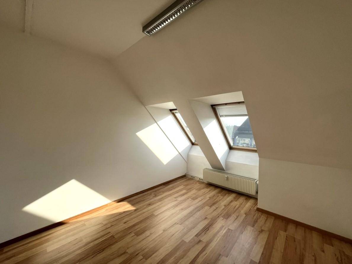 Heller Dachbodenraum mit schrägen Wänden, Dachfenstern und Laminatboden.