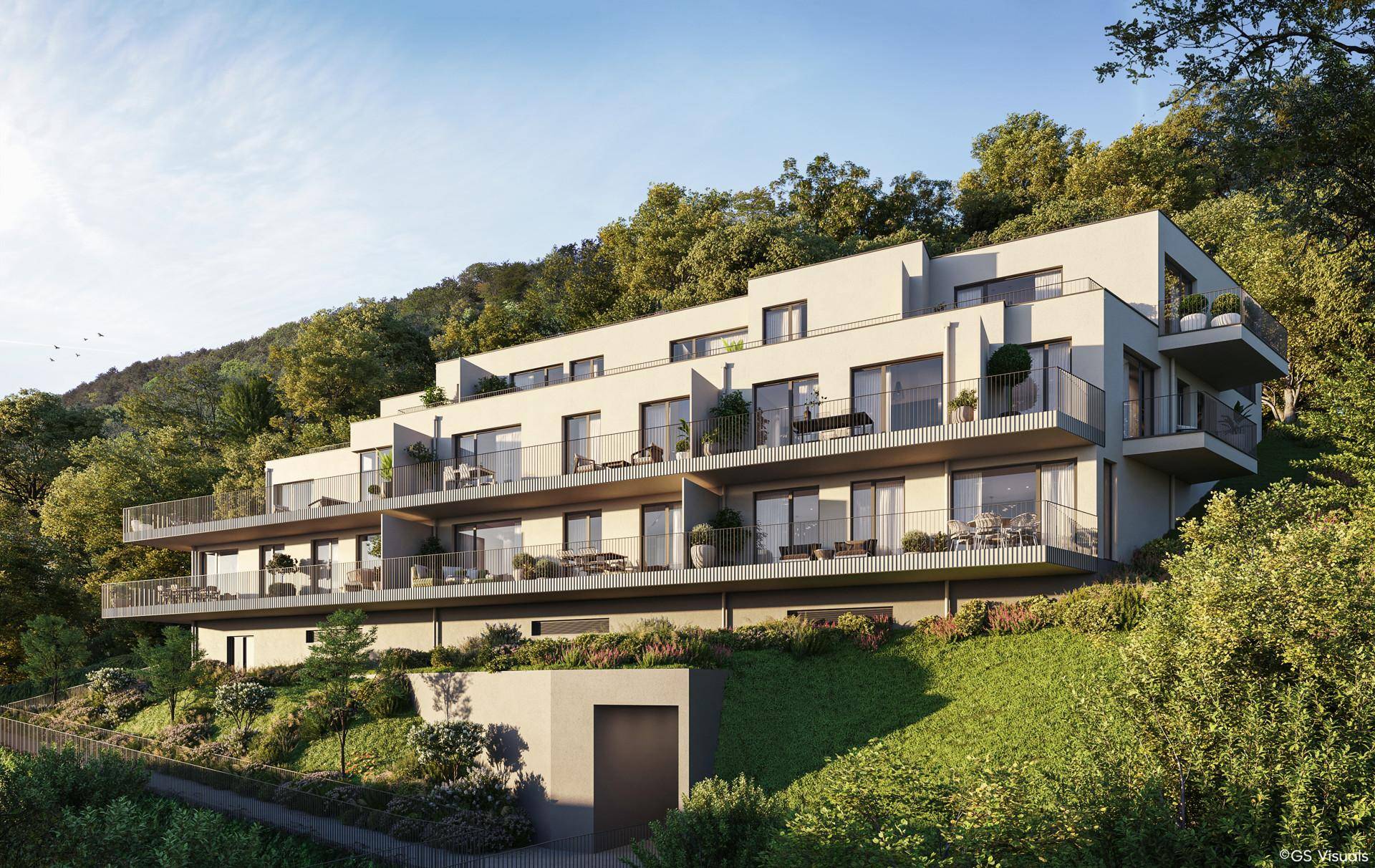 Zeitgenössisches Gebäude mit Terrassen und Balkonen, harmonisch in die hügelige Waldlandschaft integriert.