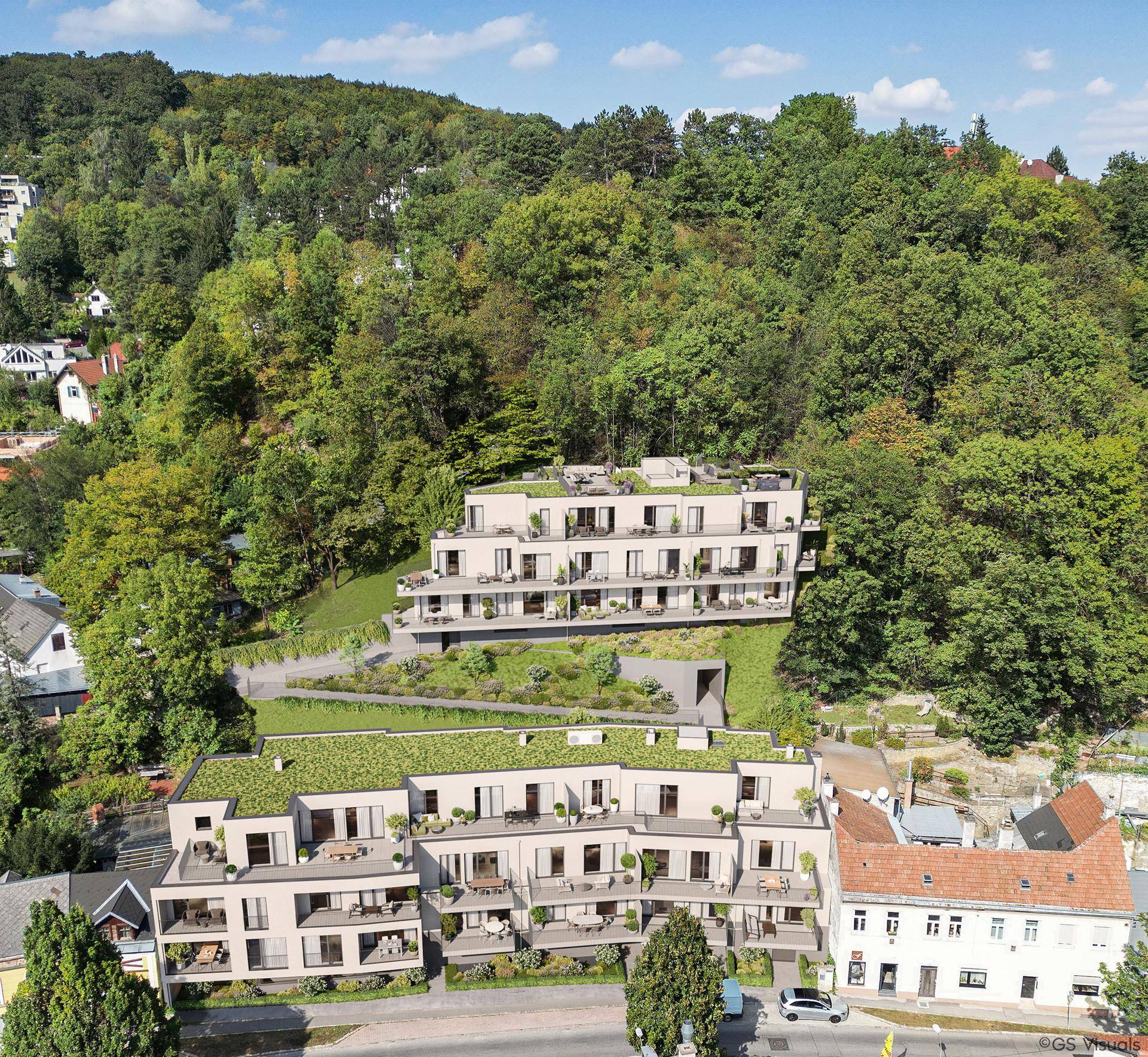 Luftaufnahme von modernen Wohngebäuden in Terrassenbauweise, eingebettet in eine grüne Hanglandschaft.