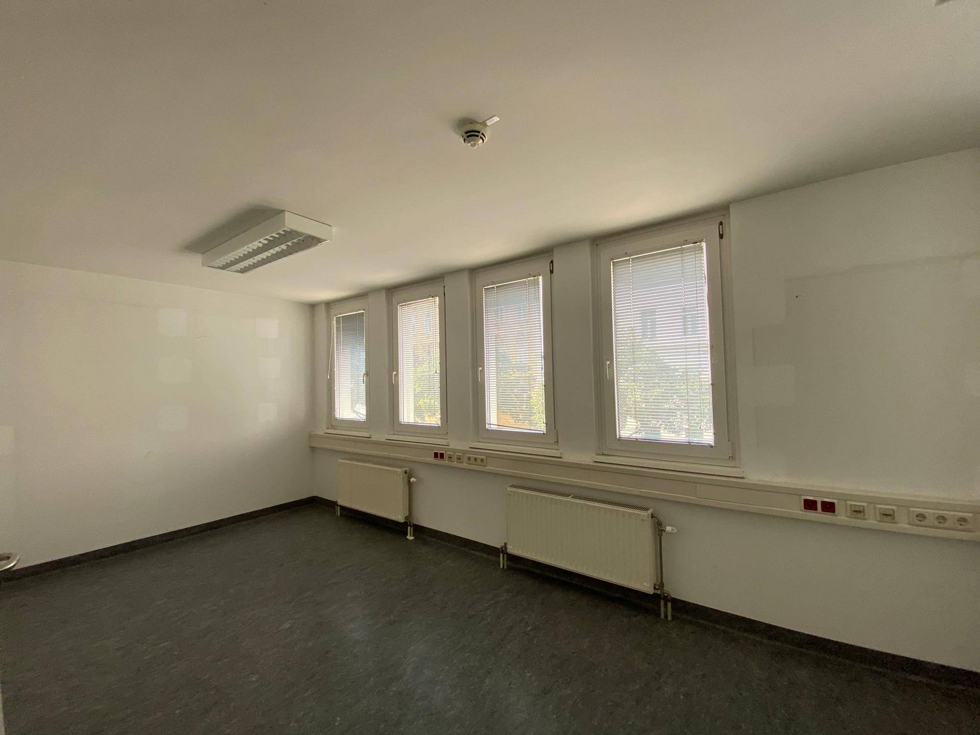 Langer, heller Büroraum mit einer Reihe von Fenstern, die den Raum mit natürlichem Licht durchfluten.