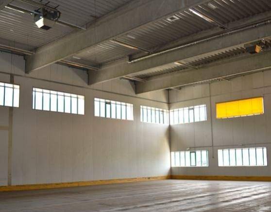 Helle Lagerhalle mit hohen Fenstern und einem gelben Akzentpanel, bietet viel Tageslicht.