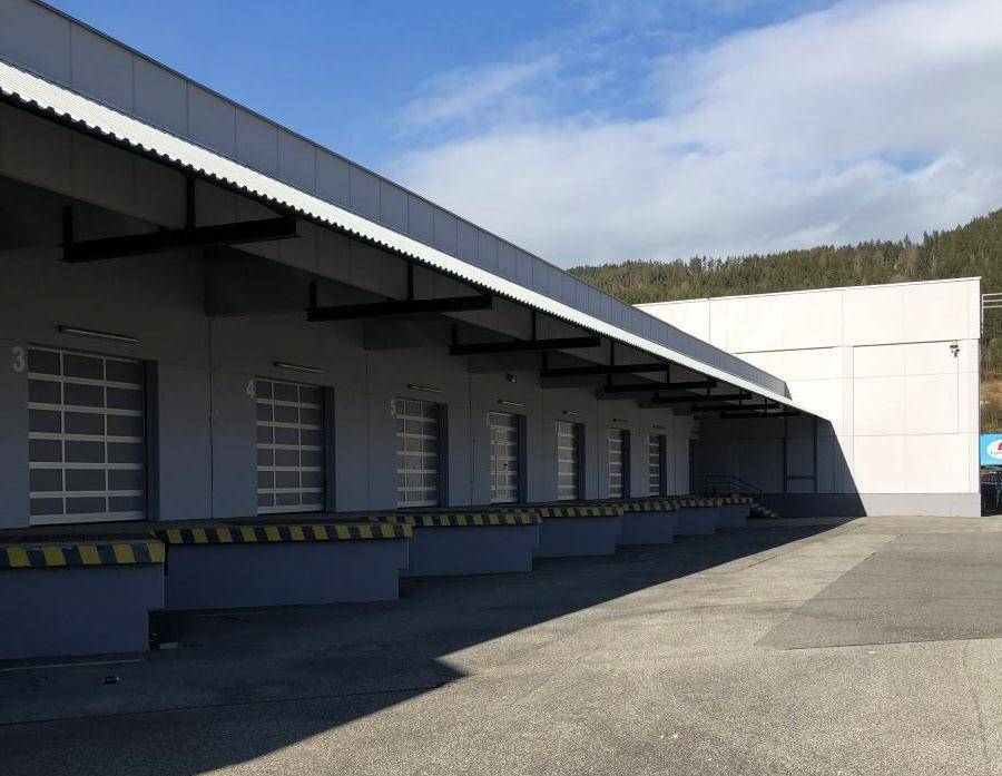 Mehrere Laderampen mit Überdachung für Lastwagen an der Rückseite der Industriehalle.