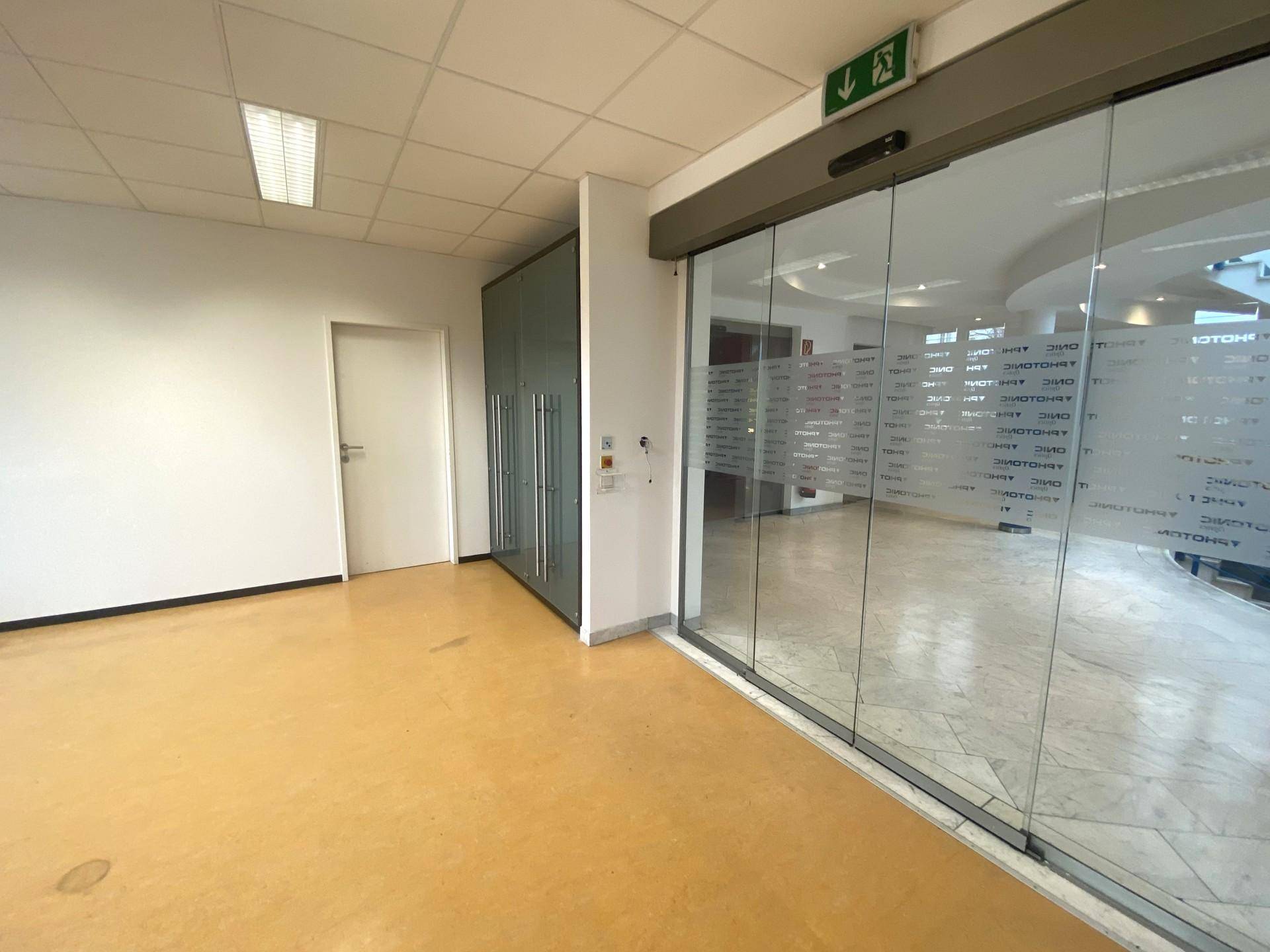 Leerer Gewerberaum mit großen Glasschiebetüren, gelbem Boden und weißen Wänden, bereit zur Gestaltung.