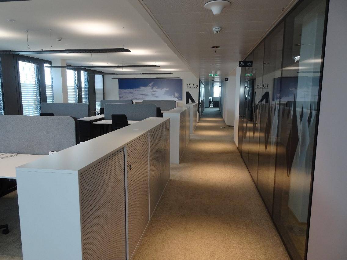 Großzügiger Großraumbüro-Bereich mit mehreren Arbeitsplätzen, Teppichboden und viel Tageslicht.