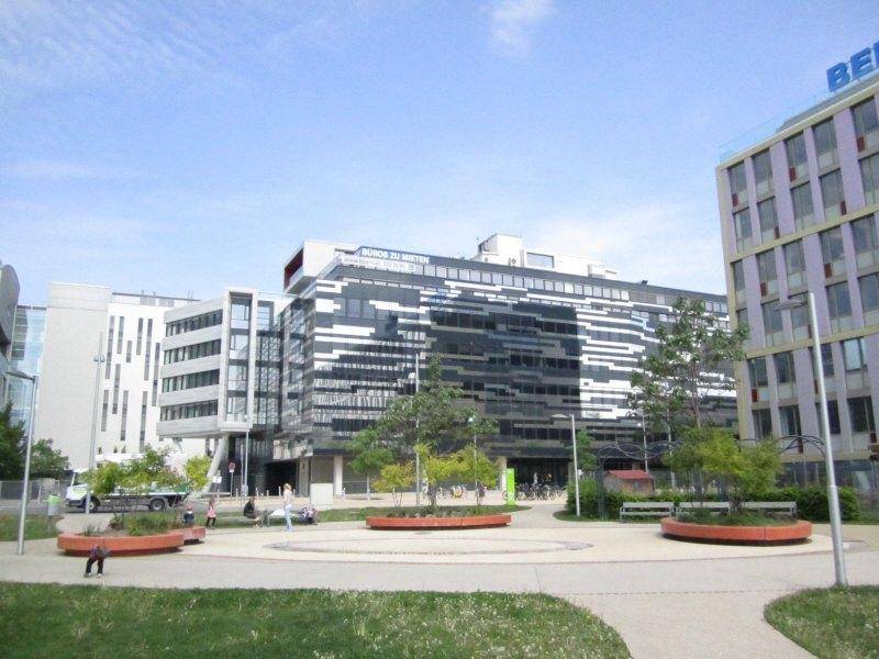 Weitläufige Ansicht des modernen Bürokomplexes mit einer Grünfläche im Vordergrund, die zum Verweilen einlädt.
