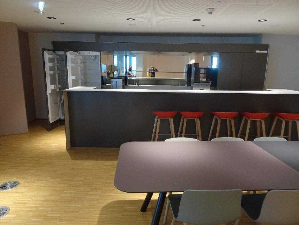Geräumige Büroküche mit moderner Theke, Barhockern und Essbereich, perfekt für Pausen und informelle Treffen.