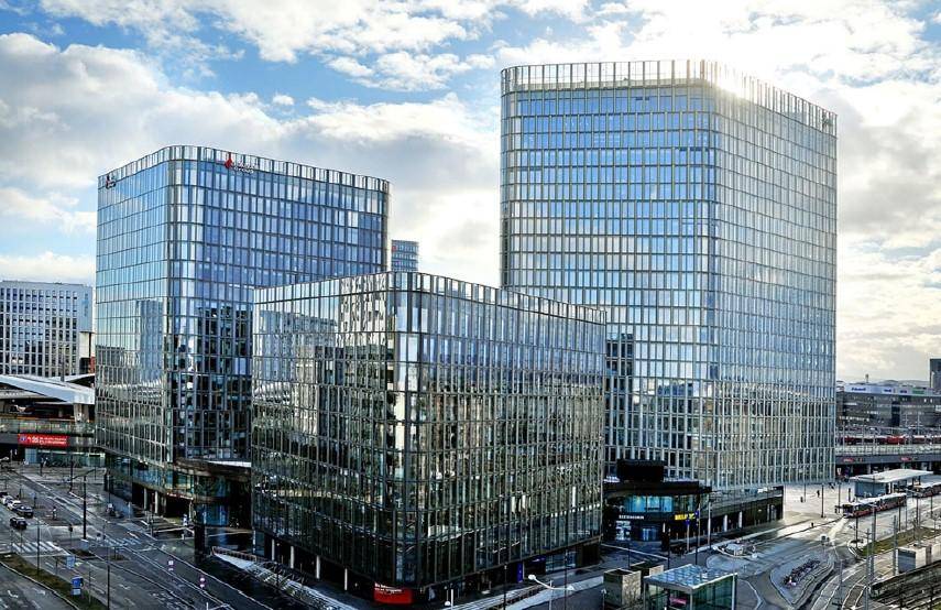 Beeindruckende moderne Bürogebäude mit Glasfassaden und zeitgenössischer Architektur unter einem bewölkten Himmel.