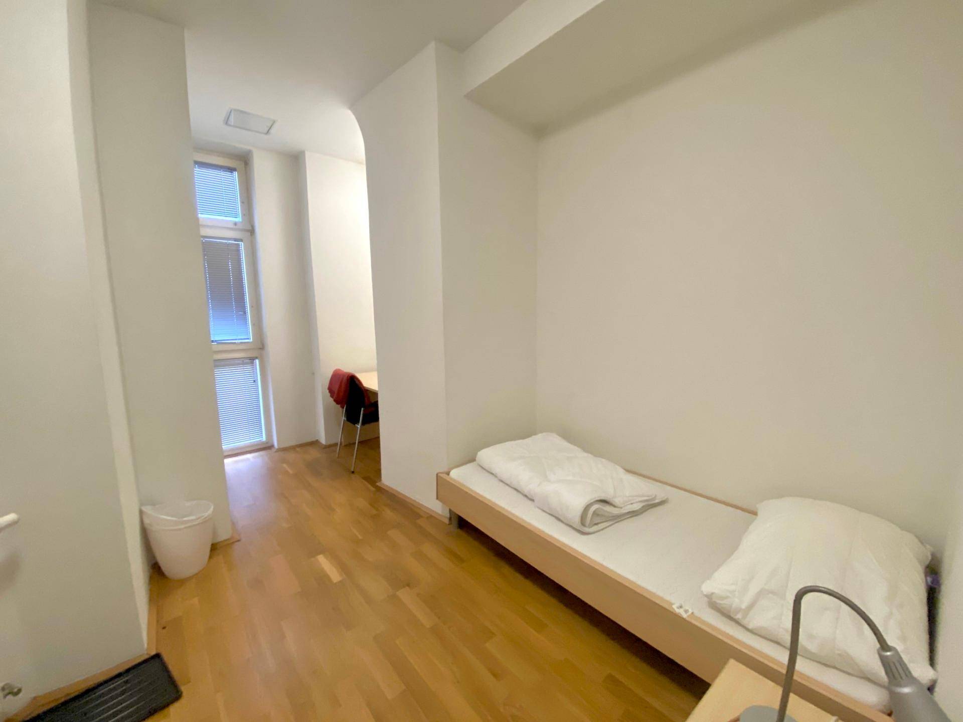 Kleines Zimmer mit einem Einzelbett und Holzboden, ideal als Ruheraum oder Gästezimmer.