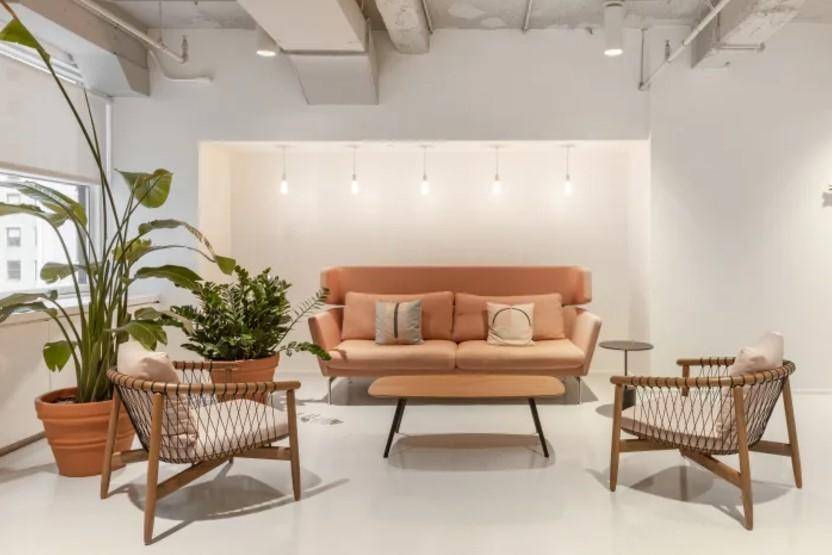 Gemütlicher Loungebereich mit beigem Sofa, Korbsesseln und großen Zimmerpflanzen.