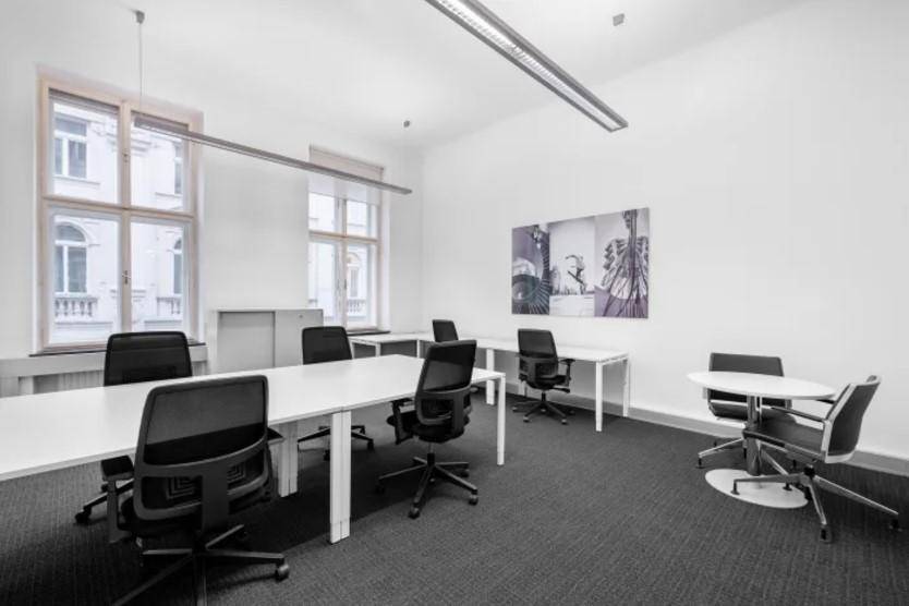 Helles Büro mit mehreren Arbeitsplätzen, großen Fenstern und Teppichboden in einem modernen Stil.