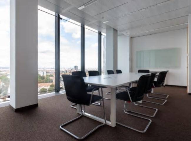 Geräumiger Konferenzraum mit langem Tisch, schwarzen Stühlen und raumhohen Fenstern mit Stadtblick.