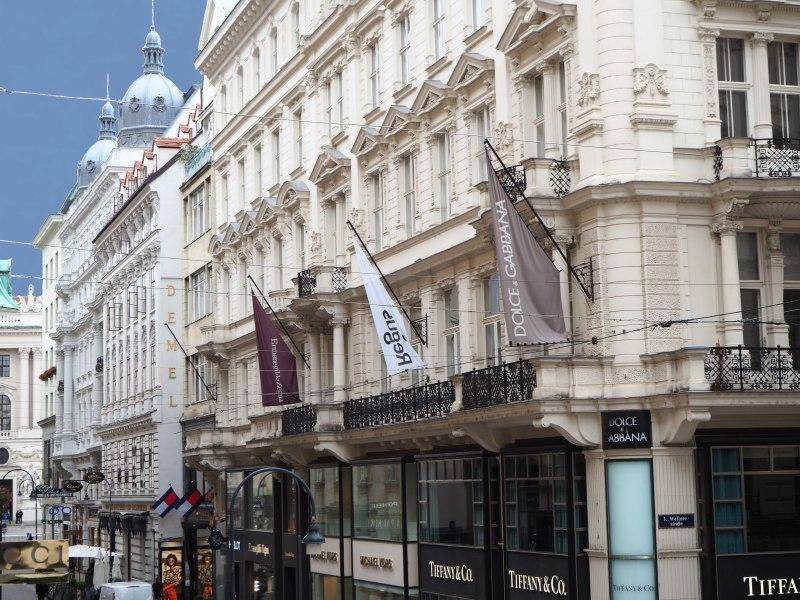 Detailansicht der historischen Fassade mit Balkonen und Geschäften im Erdgeschoss in einer städtischen Umgebung.