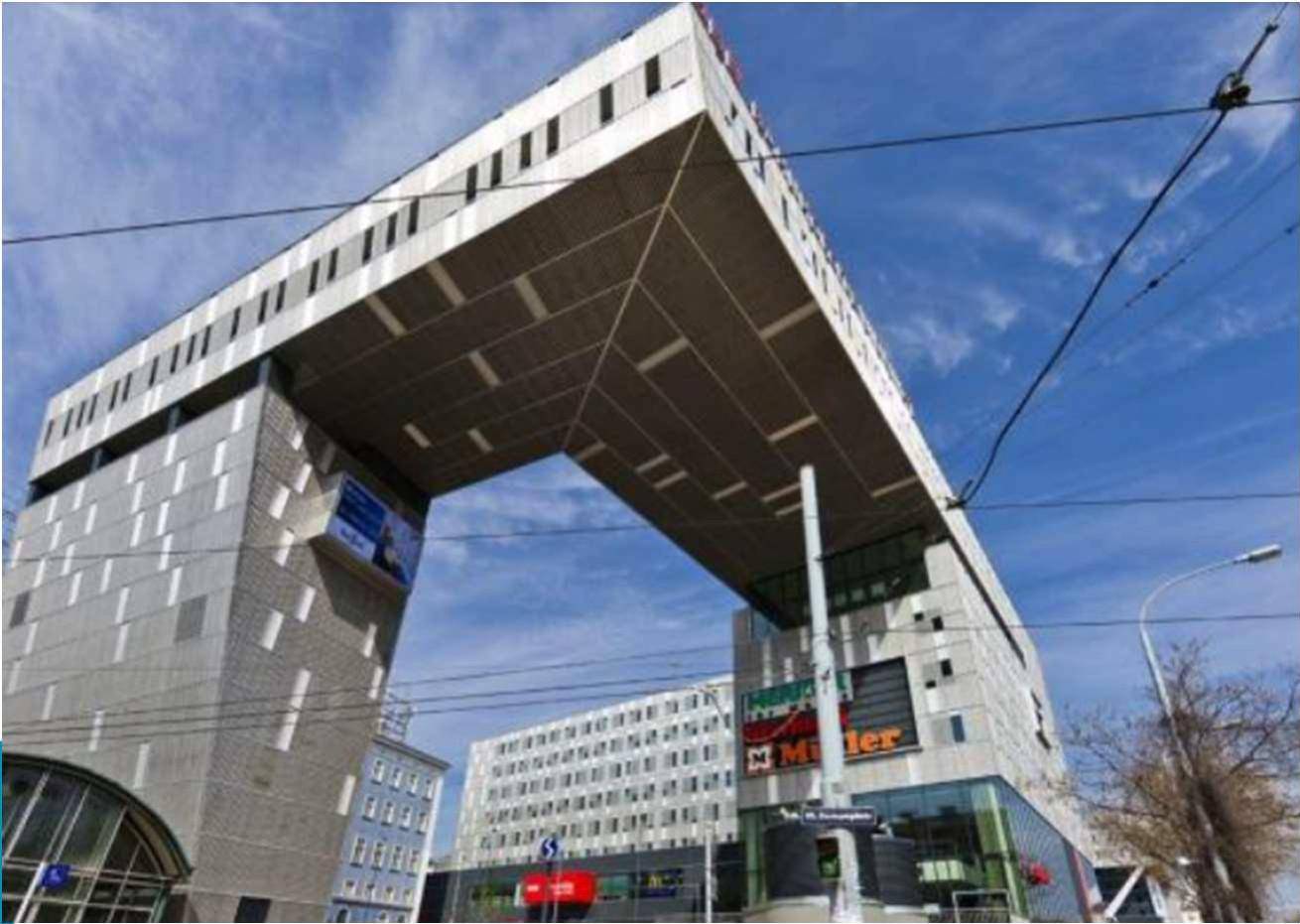 Auffälliges modernes Gebäude mit großer Überdachung und Geschäften im Erdgeschoss.