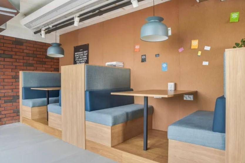 Gemütlicher Loungebereich mit Sitznischen, Holzelementen und Ziegelwand, ideal für Pausen.