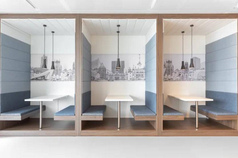 Moderne Lounge mit drei gemütlichen Sitzkabinen, kleinen Tischen und stilvoller Wanddekoration.
