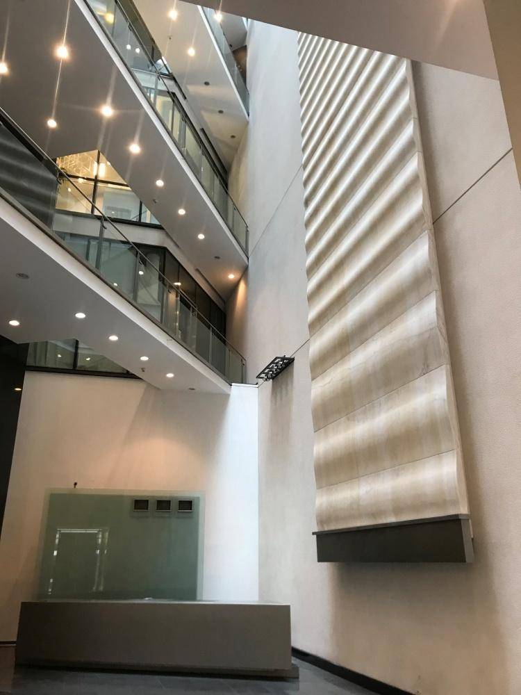 Großzügige, mehrstöckige Lobby mit modernen Glasgeländern, hohen Decken und dekorativer Wandgestaltung.