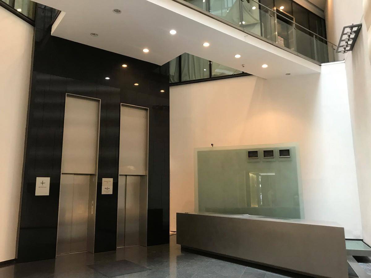Elegante Lobby mit zwei modernen Aufzügen, einem Empfangstresen und hohen Decken.