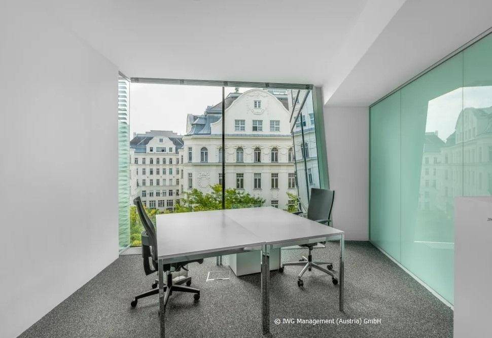 Helles Büro mit großen, schrägen Fenstern und Blick auf historische Gebäude in der Stadt.