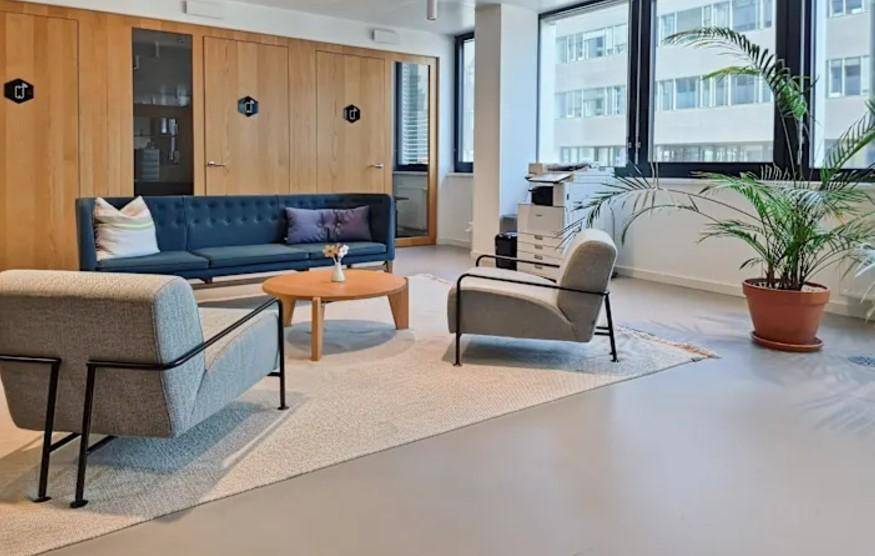 Gemütlicher Loungebereich mit bequemen Sofas, Holzwänden und großen Fenstern.