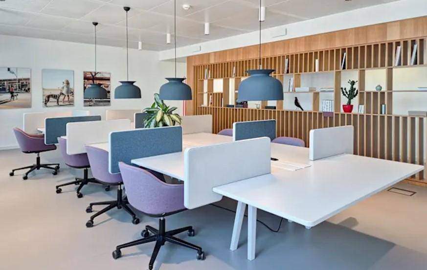 Moderner Großraumbüro mit ergonomischen Stühlen, Holzwandelementen und Pendelleuchten.